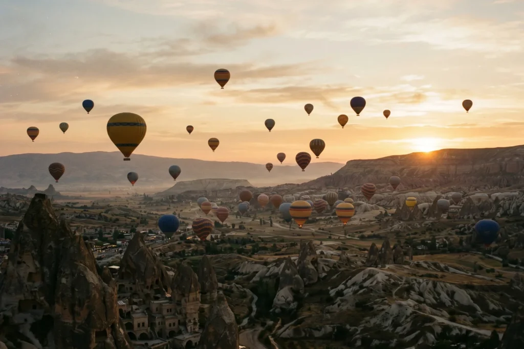 Hot air balloons over Cappadocia at dawn with a film-grain filter | Nostalgic, warm | Soft dawn golden light | Mustard, sienna, muted earth tones